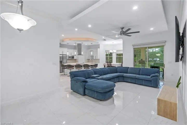 Living area featuring hanging lights, ornamental molding, a ceiling fan, and a tray ceiling