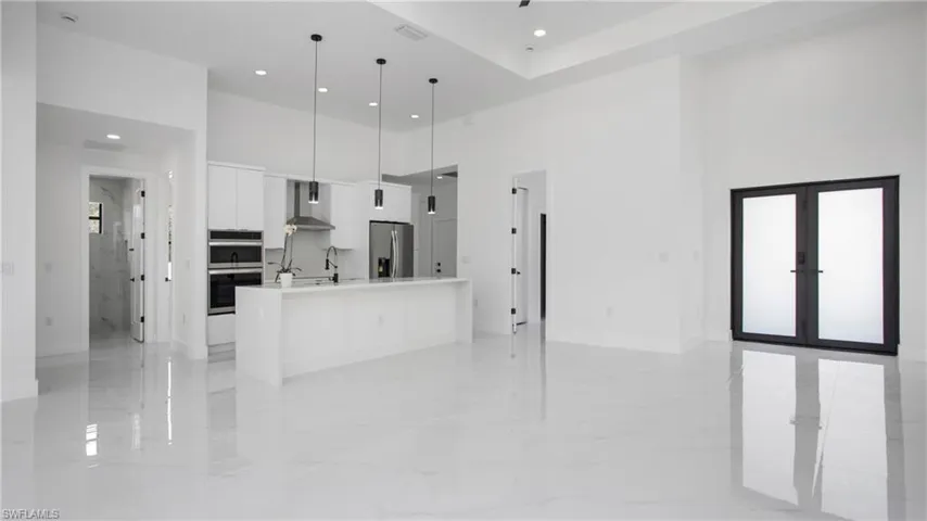 Unfurnished living room with a high ceiling, recessed lighting, and light marble finish flooring