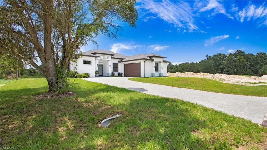 View of front of home with an attached garage, a front lawn, stucco siding, and driveway
