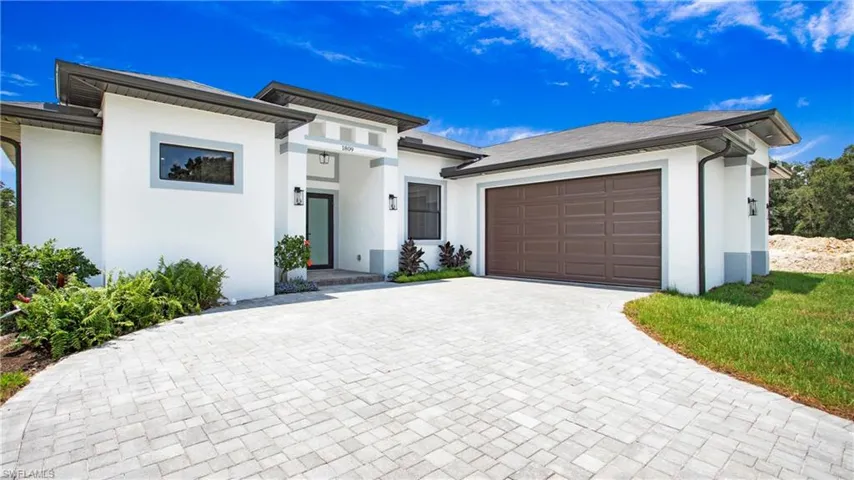 View of front of house with stucco siding, an attached garage, and decorative driveway