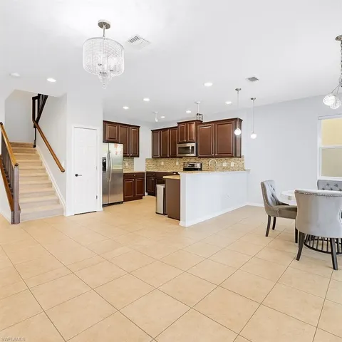 Kitchen featuring tasteful backsplash, a chandelier, light tile patterned flooring, light countertops, and pendant lighting