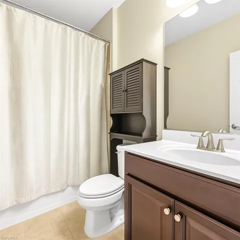 Bathroom with light tile patterned floors, vanity, and shower / bath combo with shower curtain