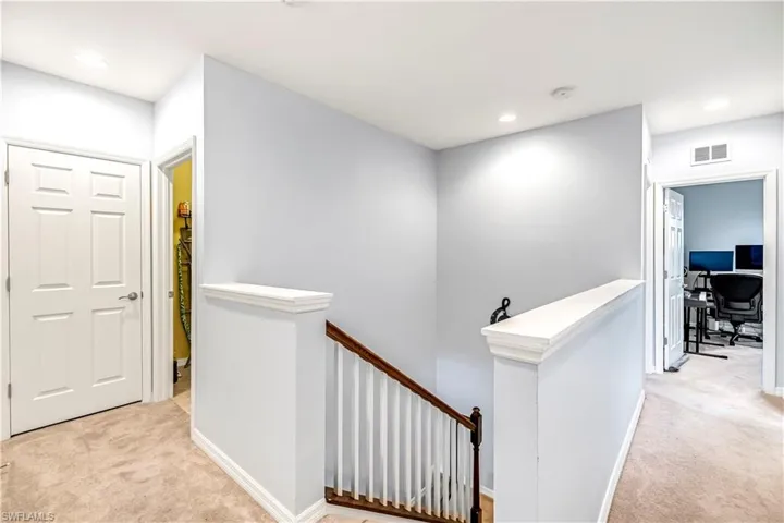 Corridor featuring light carpet, an upstairs landing, a desk, and recessed lighting