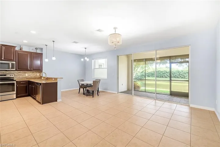 Kitchen with light tile patterned floors, stainless steel appliances, hanging light fixtures, a peninsula, and a chandelier