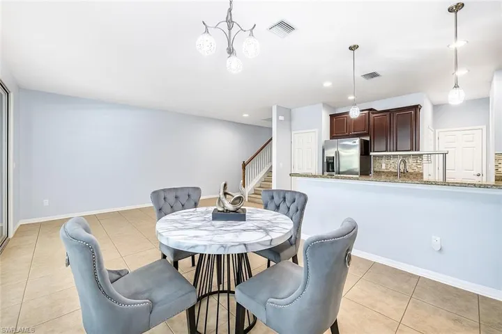 Dining space with light tile patterned floors, stairway, recessed lighting, and a chandelier