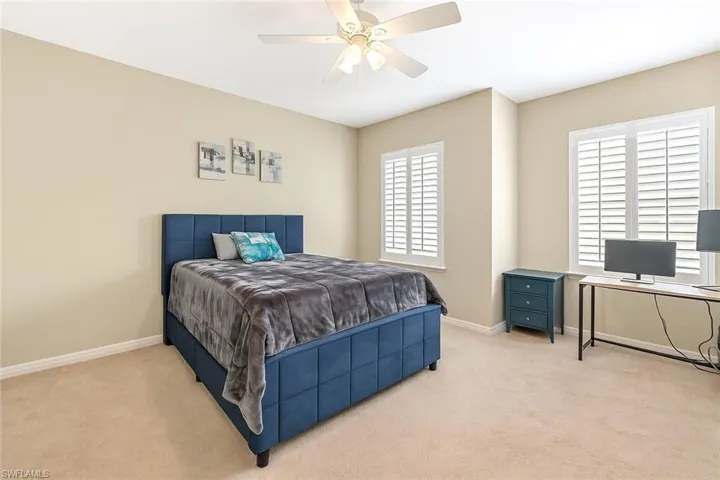 Carpeted bedroom featuring ceiling fan and an office area