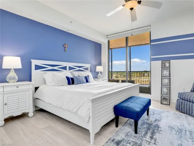 Bedroom featuring ceiling fan, hardwood / wood-style floors, a wall of windows, and access to exterior