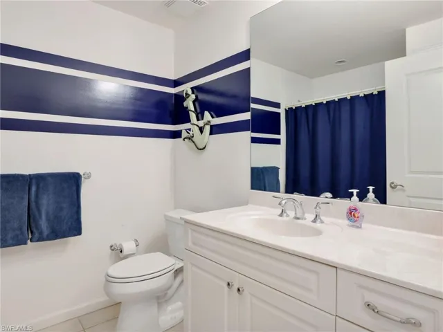 Bathroom featuring tile flooring, toilet, and large vanity