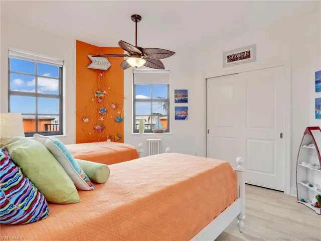 Bedroom featuring a closet, ceiling fan, light wood-type flooring, and multiple windows