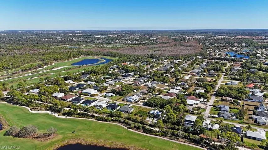 Expansive residential area with a golf course, multiple water features, and abundant mature trees