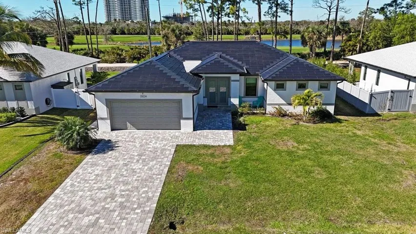 Contemporary single-story residence with a dark-tiled roof, light-colored exterior, and a paver driveway