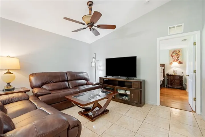 Living room featuring light tile patterned floors, vaulted ceiling, and ceiling fan
