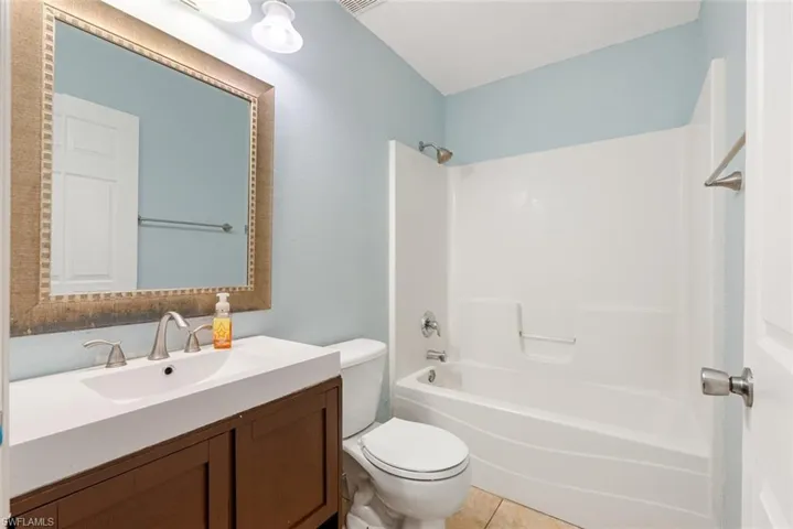 Full bathroom with vanity, bathtub / shower combination, tile patterned floors, and toilet