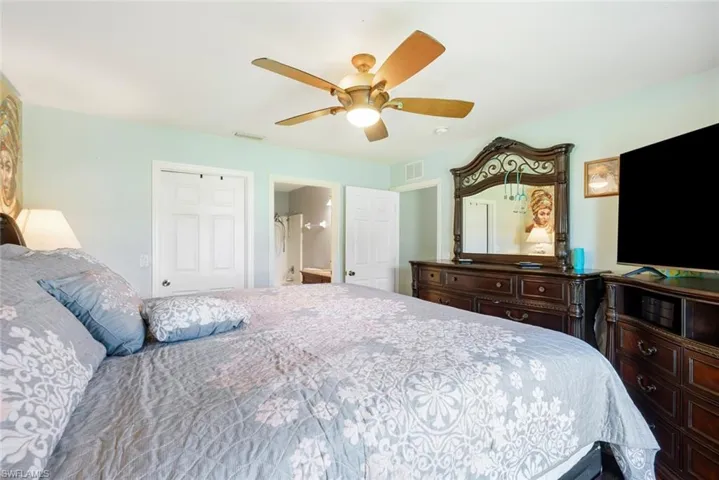 Bedroom featuring a closet, ensuite bath, and ceiling fan