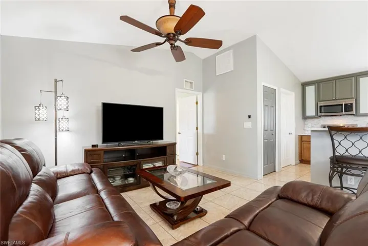 Tiled living room with high vaulted ceiling and ceiling fan