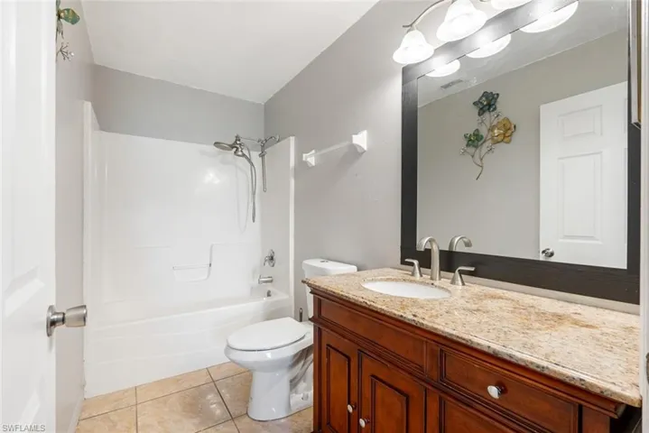 Full bathroom with vanity, tub / shower combination, tile patterned flooring, and toilet