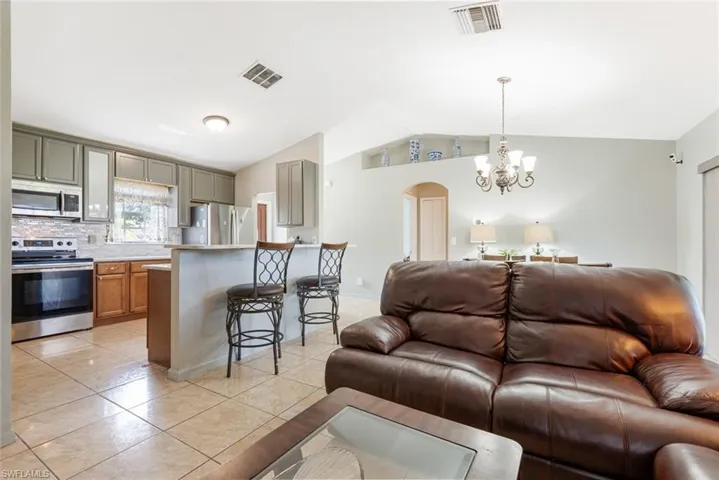 Tiled living room with an inviting chandelier and vaulted ceiling