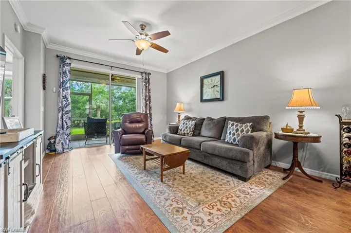 Living room featuring hardwood / wood-style flooring, ceiling fan, and crown molding