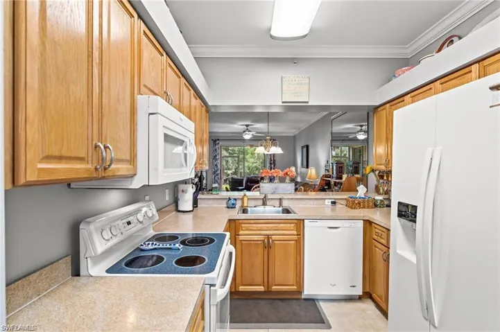 Kitchen with sink, crown molding, pendant lighting, white appliances, and light tile patterned flooring