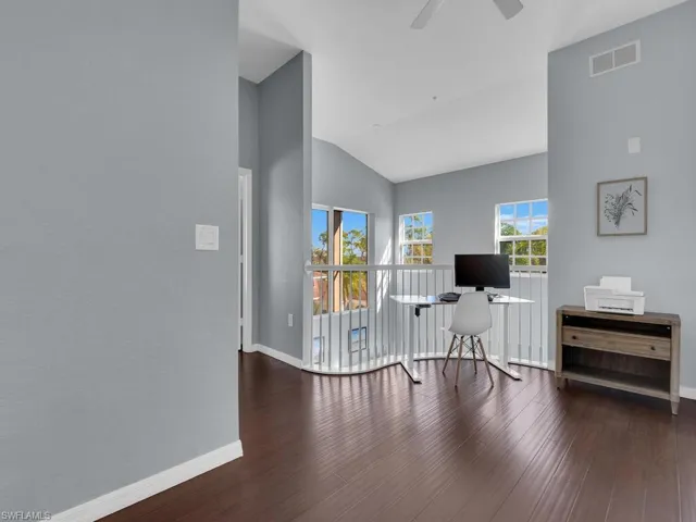 Home office with vaulted ceiling, dark wood-type flooring, and ceiling fan