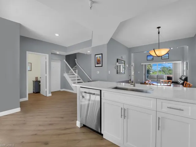 Kitchen with white cabinets, open floor plan, stainless steel dishwasher, hanging light fixtures, and light wood-style flooring