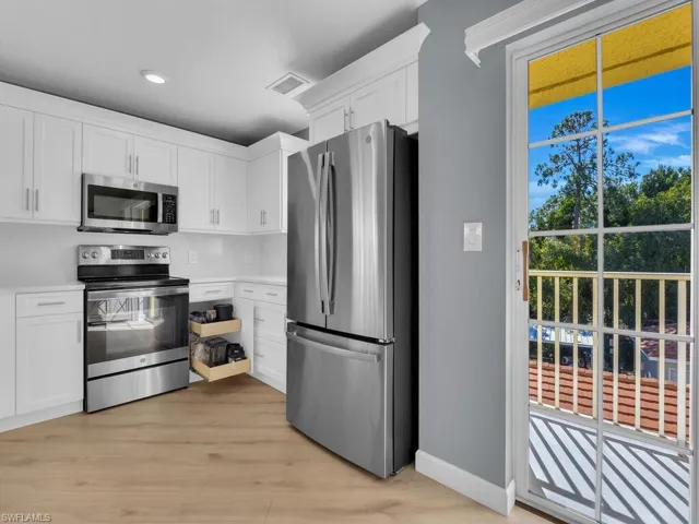 Kitchen with stainless steel appliances, white cabinetry, light countertops, light wood-style floors, and recessed lighting