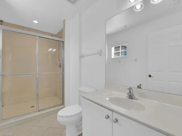 Full bath featuring vanity, a stall shower, light tile patterned flooring, and recessed lighting