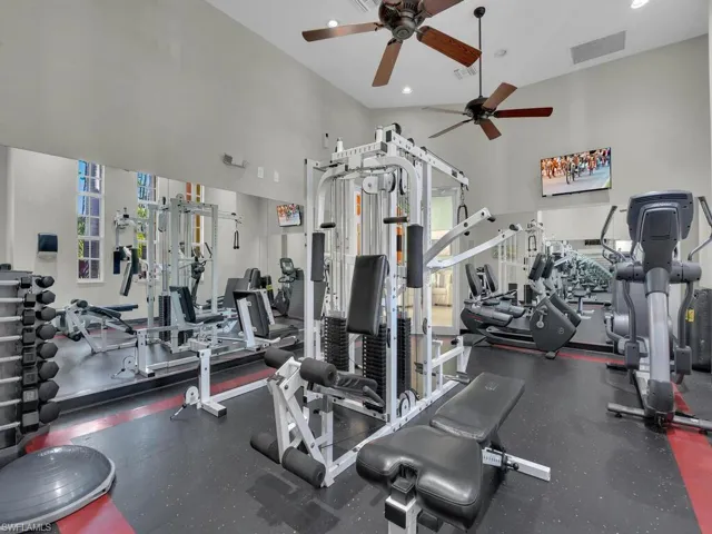 Exercise room with a ceiling fan, a high ceiling, and recessed lighting