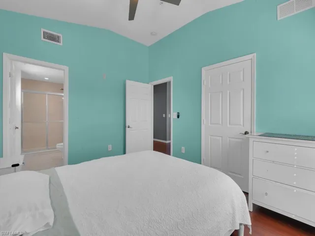 Bedroom with vaulted ceiling, dark wood finished floors, and ceiling fan