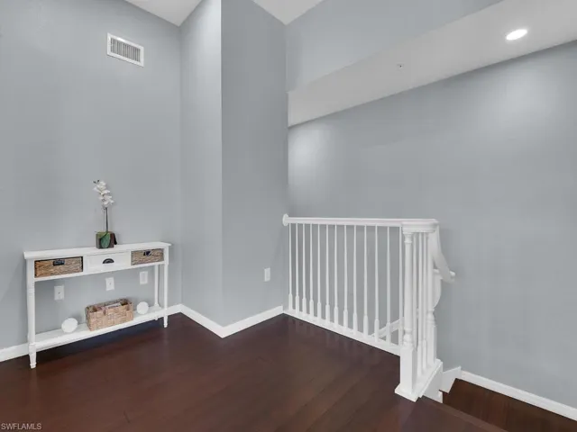 Spare room featuring baseboards and dark wood-style flooring