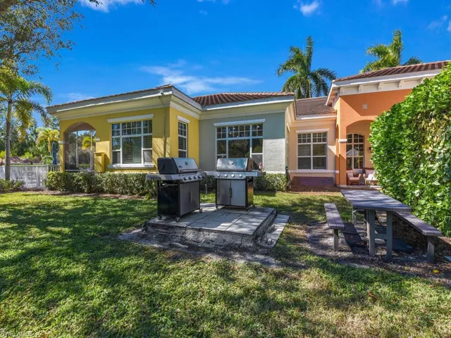 Back of property featuring stucco siding, a tile roof, a patio area, and a yard
