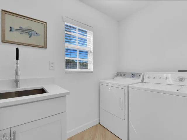 Laundry area featuring light wood-style flooring, washer and dryer, and cabinet space