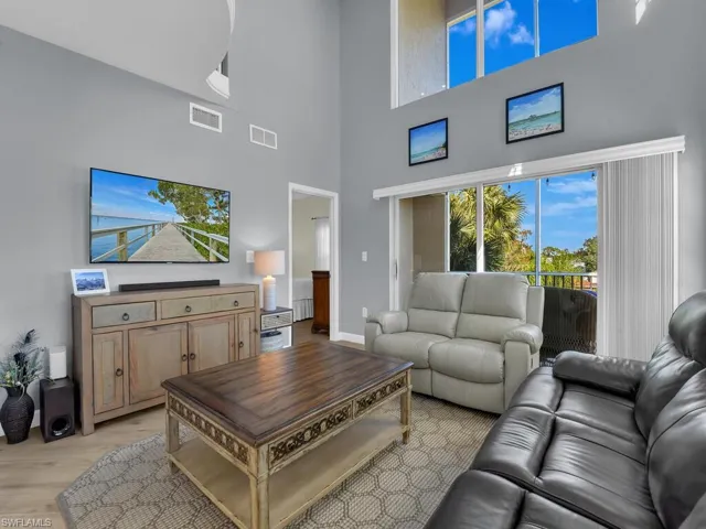 Living room featuring light wood-style flooring and a high ceiling