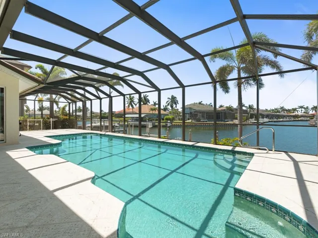 Pool featuring a water view, glass enclosure, and a patio