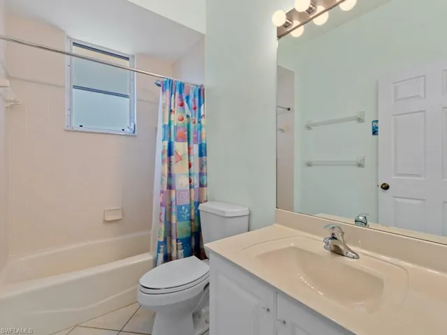Full bath with tile patterned flooring, shower / bath combo with shower curtain, vanity, and toilet