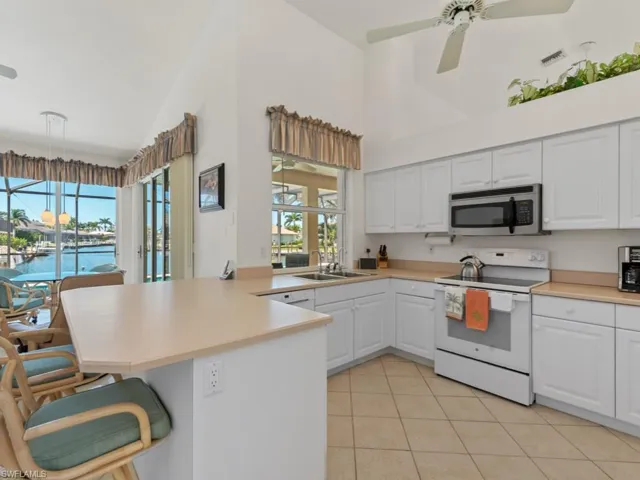 Kitchen featuring visible vents, a sink, white range with electric cooktop, a peninsula, and stainless steel microwave