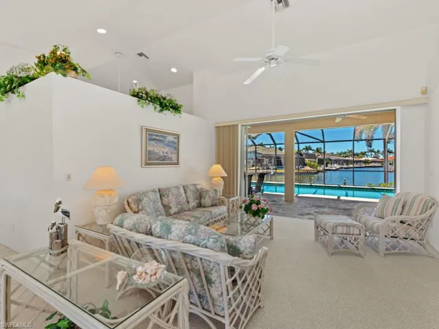 Carpeted living area featuring a water view, visible vents, ceiling fan, high vaulted ceiling, and a sunroom