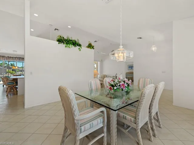 Dining room with light tile patterned flooring, an inviting chandelier, and vaulted ceiling