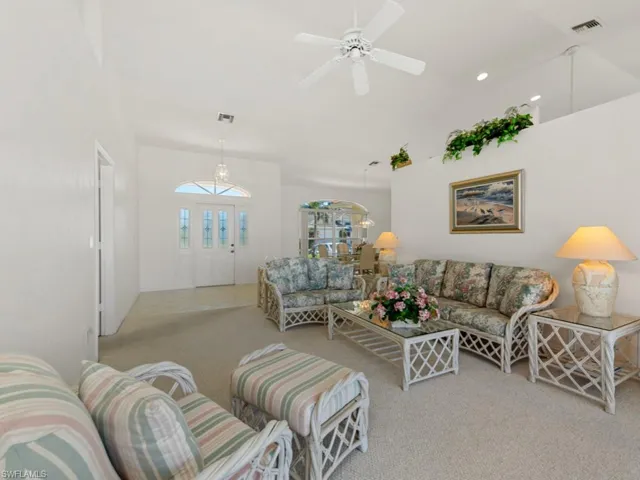 Carpeted living room featuring recessed lighting, visible vents, vaulted ceiling, and a ceiling fan