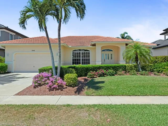 View of front facade featuring a tiled roof, stucco siding, a front yard, an attached garage, and concrete driveway