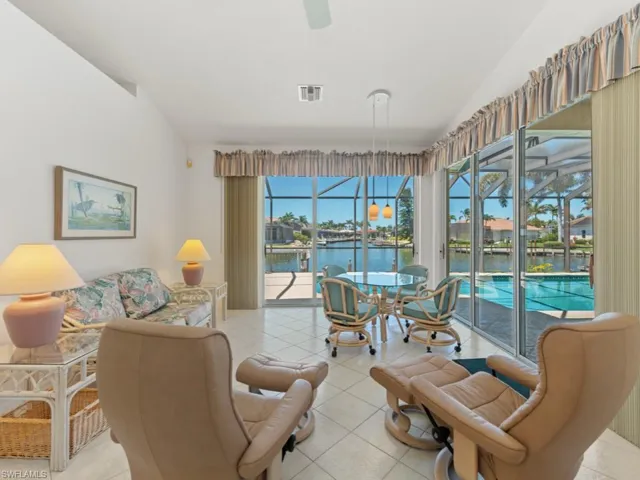 Living room featuring visible vents, a sunroom, a water view, a ceiling fan, and vaulted ceiling
