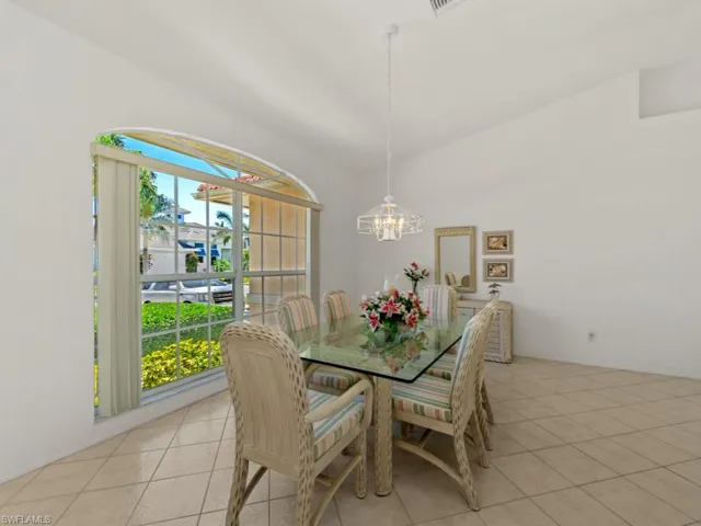 Dining space featuring light tile patterned floors, plenty of natural light, a notable chandelier, and lofted ceiling