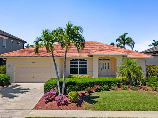 Mediterranean / spanish house with a garage, driveway, stucco siding, and a tiled roof