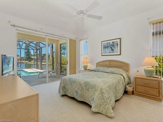 Carpeted bedroom featuring multiple windows, access to outside, a sunroom, and a ceiling fan