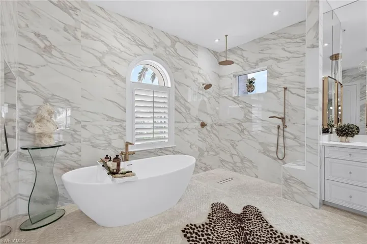 Full bathroom with a marble finish shower, vanity, stone wall, a freestanding tub, and recessed lighting