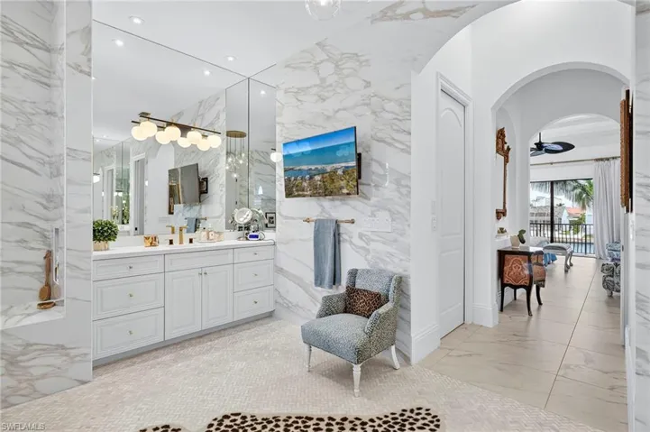 Bathroom featuring vanity, light marble finish flooring, recessed lighting, ceiling fan, and stone wall