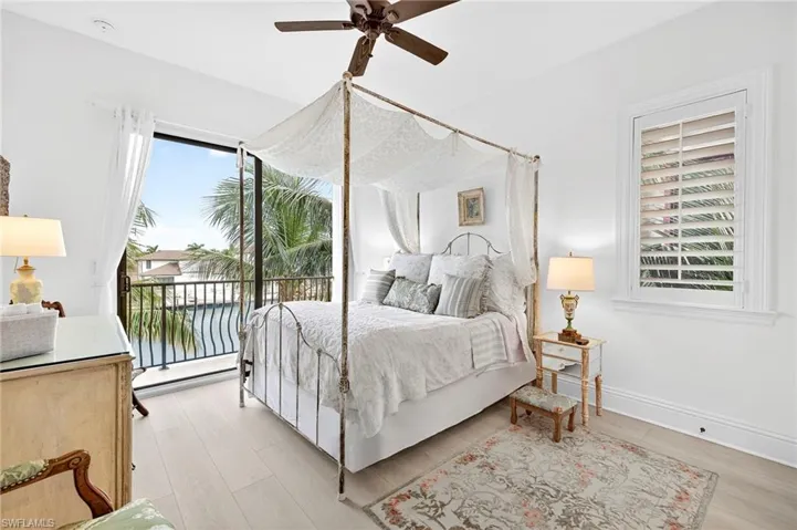 Bedroom featuring access to exterior, ceiling fan, light wood-style floors, and a water view