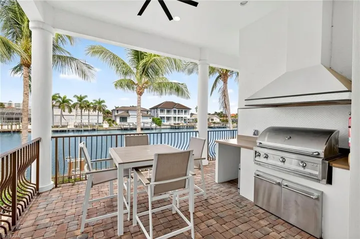 View of patio / terrace featuring exterior kitchen, a water view, ceiling fan, and outdoor dining space