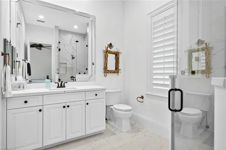 Full bathroom with a marble finish shower, vanity, and light marble finish floors