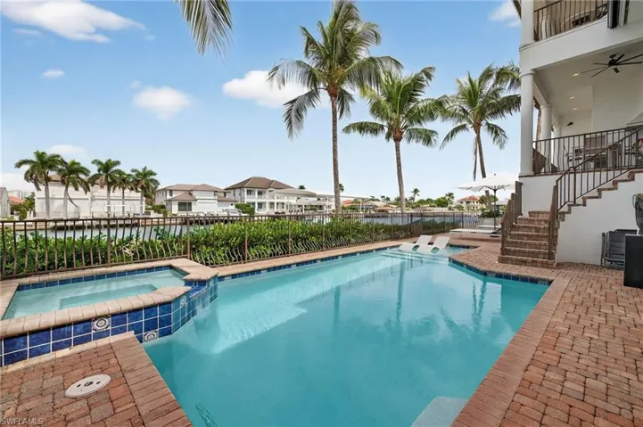 View of swimming pool featuring stairway, a patio, a pool with connected hot tub, and a balcony